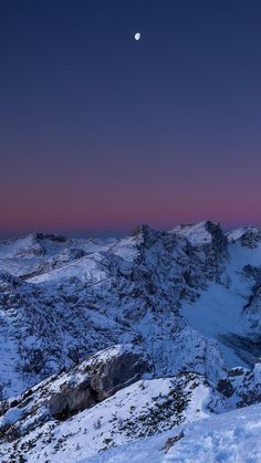 the moon shines brightly in the sky above snowy mountains