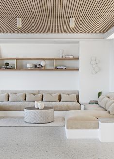 a living room filled with lots of furniture next to a wall mounted book shelf on top of a wooden ceiling