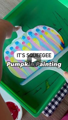 a child is painting a pumpkin on a green tray with the words, it's squeezee pumpkin painting