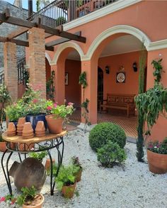 an outdoor patio with potted plants and pots on a table in front of it