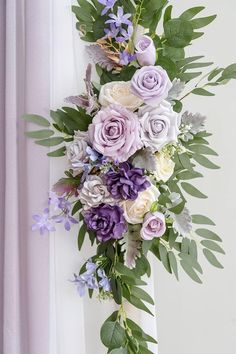 a bouquet of flowers hanging from the side of a window sill with greenery