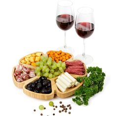 two glasses of wine and some food on a tray with grapes, broccoli