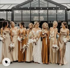 a group of women standing next to each other wearing dresses and holding bouquets in their hands