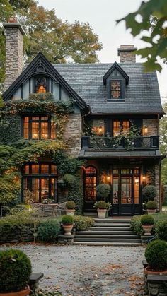 a large house with lots of windows and plants on the front porch, surrounded by trees