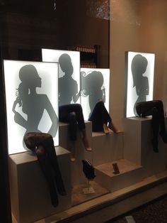 three mannequins are sitting on display with their shadows projected over them in the window