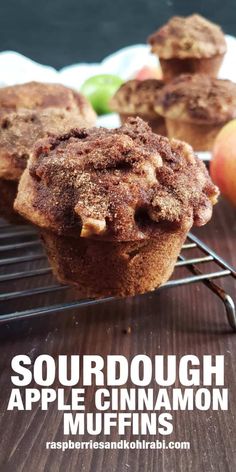 an apple cinnamon muffin on a cooling rack with apples in the background and text overlay that reads sourdough apple cinnamon muffins