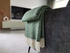 a green blanket sitting on top of a black couch