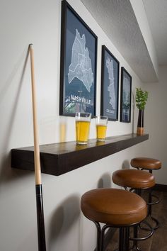 a row of bar stools sitting next to a wall with three framed pictures on it