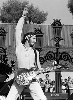 a man with a guitar on stage in front of a large group of people watching