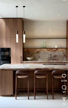 a kitchen with two stools and an island in the middle, surrounded by wooden cabinets