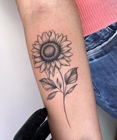 a woman's arm with a sunflower tattoo on it