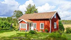 a small red house sitting on top of a lush green field