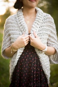 a woman wearing a white crochet shawl and holding her hands together in front of her chest