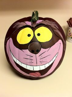 a painted pumpkin with an evil face on it's side and some candy in the background