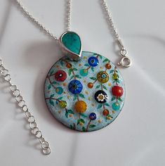 Multi color vitreous enamel on copper pendant with milliefiori beads and seed beads.  Total length : 4.2 cm.  Enamel part: 3.3 cm in diameter. Turquoise gemstone bezel: 9 mm x 13 mm.  The pendant comes with 45 cm sterling silver 925 chain.  Every enameled piece is kiln fired at least 6-7 times at around 1400oF. Special enamel painting set is used for the branches and leaves, and kiln fired at around 1280oF.  Enamel piece is attached to the sterling silver bail with turquoise gemstone. All connections are soldered.  NILAJ brand mark is available. What you see is what you get, the item seen on this listing will be shipped in one business day.  I use the Turkish International Postal Service which takes 3-4 weeks to the North America and 2-3 weeks to Europe.  Please contact me if you have any Enameled Jewelry, Enamel Painting, Enamel Jewellery, Brand Mark, Fish Jewelry, Gemstone Art, Vitreous Enamel, Enameled Copper, Painting Set