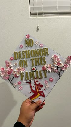 someone holding up a graduation cap that says no dishonor on this family with flowers all over it