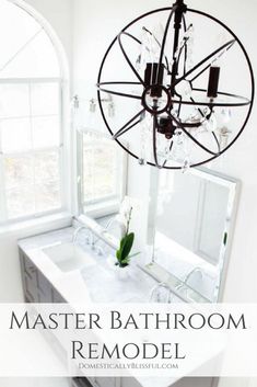 a bathroom with a chandelier hanging from the ceiling and a mirror above it