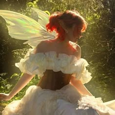 a woman dressed as a fairy sitting on the ground