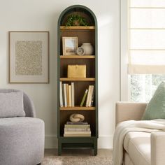 a living room filled with furniture and a tall book shelf next to a chair in front of a window