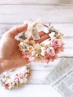 a hand holding a flower crown on top of a white table