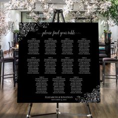 a black and white wedding seating plan on a easel in front of a floral centerpiece