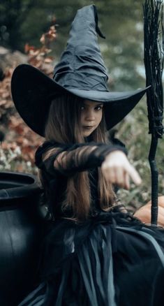 a woman dressed as a witch sitting on the ground