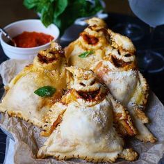 several pieces of pizza sitting on top of a piece of wax paper next to a bowl of sauce