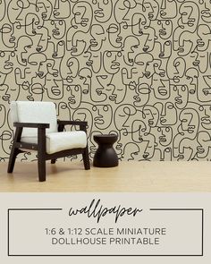 a chair and table sitting in front of a wallpaper with black faces on it