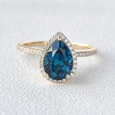 a blue and white diamond ring sitting on top of a white surface with diamonds around it