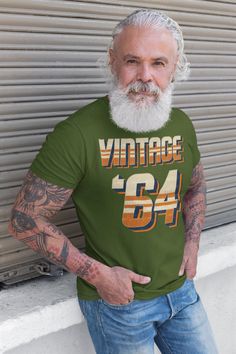 "Men's Vintage '64 Birthday T Shirt 60th Birthday Shirt Sixty Years Gift Grunge Retro Stripe Bday Gift Men's Unisex 1964 Bday Unisex Man Gift Idea The vintage retro design on this 60th birthday shirt will never go out of style. A great gift idea for someone born in 1964 turning 60 in 2024. The design reads 'Vintage, '64' in a distressed striped style that features a nostalgic retro look. We only print on super soft, ring spun cotton. Includes our signature satin lined drawstring bag. Our model is wearing Military Green. Check out our other Etsy listings: http://shirtsbysarah.etsy.com Check out our other Etsy Shop: https://shirtsbysarahtotes.etsy.com Men's/Unisex Sizing: RUNS SMALL This shirt is made from soft ring spun cotton. Solid Colors Are 100% Cotton Vintage colors are 50% cotton/poly 60th Birthday Shirt, 64th Birthday, Bday Gift, Retro Stripes, Mens Formal, Crew Neck Shirt, 60th Birthday, Soft Ring, Birthday Shirt