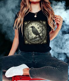 Step into the enchanting world of the occult with our Gothic Raven Shirt! This unique tee features a stunning Tarot Card Raven design that's perfect for those with a taste for the dark, mystical, and whimsical. Whether you're drawn to dark academia, witchy vibes, or goblincore aesthetics, this shirt is an essential addition to your wardrobe. .: 100% Airlume combed and ringspun cotton  .: Light fabric  .: Tear away label .: Runs true to size Bella + Canvas Brand Shirt ▶For oversized options pleas Halloween Goblincore T-shirt With Graphic Print, Halloween Goblincore Graphic T-shirt, Halloween Fairy Grunge T-shirt With Crew Neck, Fairy Grunge Halloween T-shirt With Crew Neck, Black Goblincore Tops For Halloween, Halloween Goblincore Crew Neck Top, Black Goblincore Top With Graphic Print, Goblincore Halloween Short Sleeve T-shirt, Goblincore Halloween T-shirt With Short Sleeves