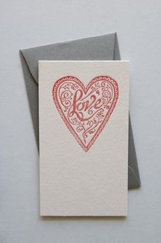 a card with the word love written on it and a red heart in the middle