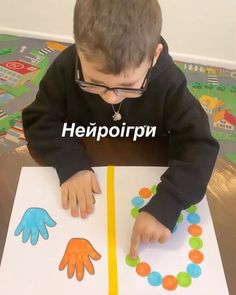 a young boy is sitting at a table and playing with his hands on the paper