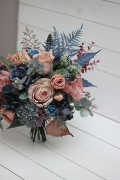 a bouquet of flowers sitting on top of a white wooden table next to a wall