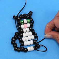 a person is making a beaded cat ornament