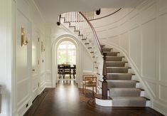 a staircase leading up to a dining room table and chairs on the other handrail