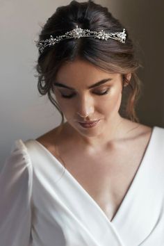 a woman wearing a white dress and a headband with crystal stones on the side