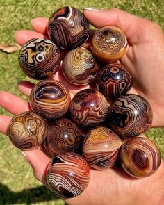 a person is holding many marbles in their hand on the grass and there are other marbles