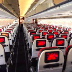 rows of empty seats in an airplane with red lights on the front and back ends