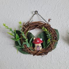 a wreath hanging on the wall with a mushroom house in it