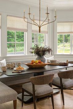 a dining room table with chairs and a bowl of fruit on top of the table