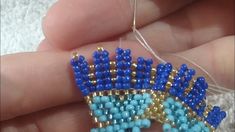 the beading is being worked on by someone's hand and they are holding something in their left hand