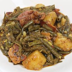 a white plate topped with green beans and potatoes