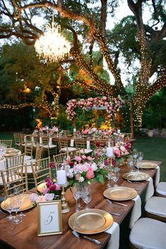 an outdoor dinner table set up with place settings and floral centerpieces for the tables