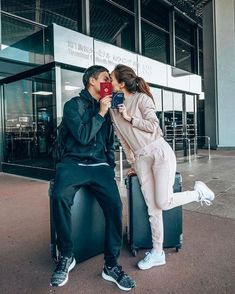 a man and woman kissing while sitting on luggage