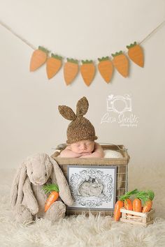 a baby is laying in a crate with carrots and a bunny hat on it