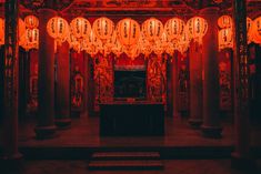 lanterns hanging from the ceiling in front of a window with chinese writing on it and red lighting