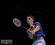 a man hitting a tennis ball with a racquet on a dark background at night