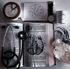 an open book sitting on top of a table next to a cup of coffee and scissors