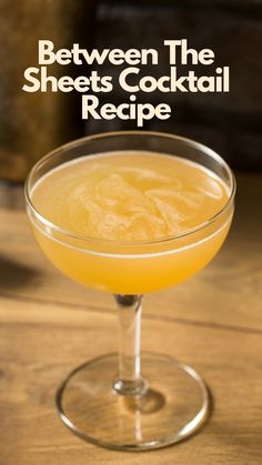 an orange cocktail in a coupe glass with the words between the sheets cocktail recipe on it